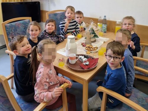 Die Kinder sitzen am Tisch und essen einen Snack.
