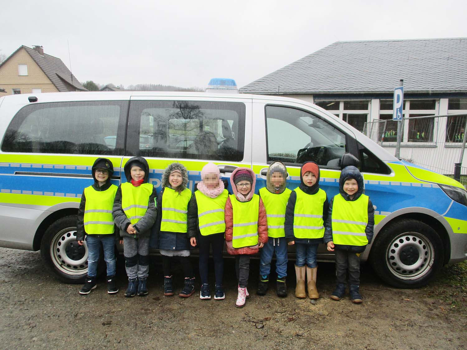 8 Kinder stehen vor einem Polizeiwagen