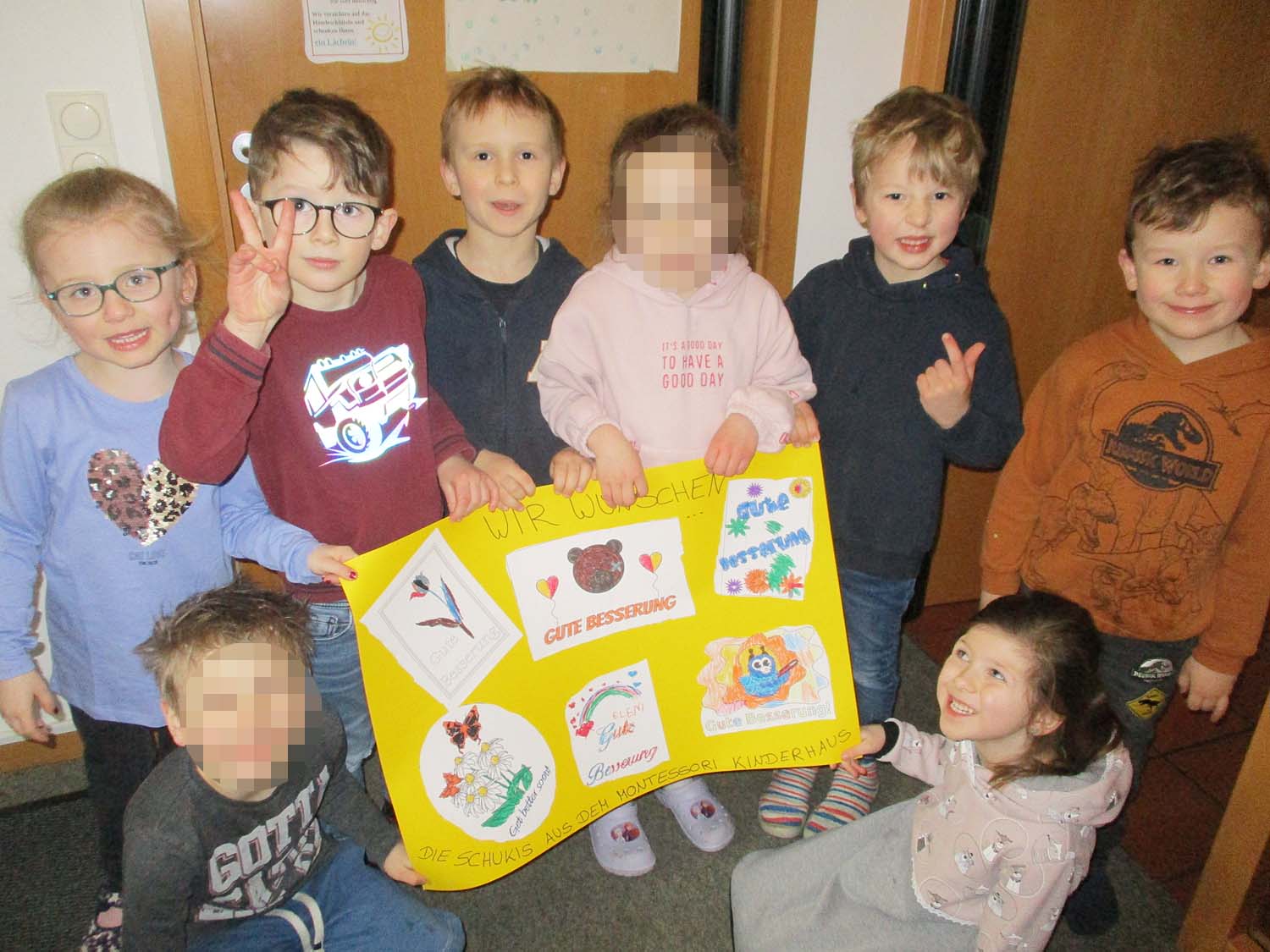 4 Kinder halten ein Plakat, 2 knien davor, 2 stehen rechts daneben